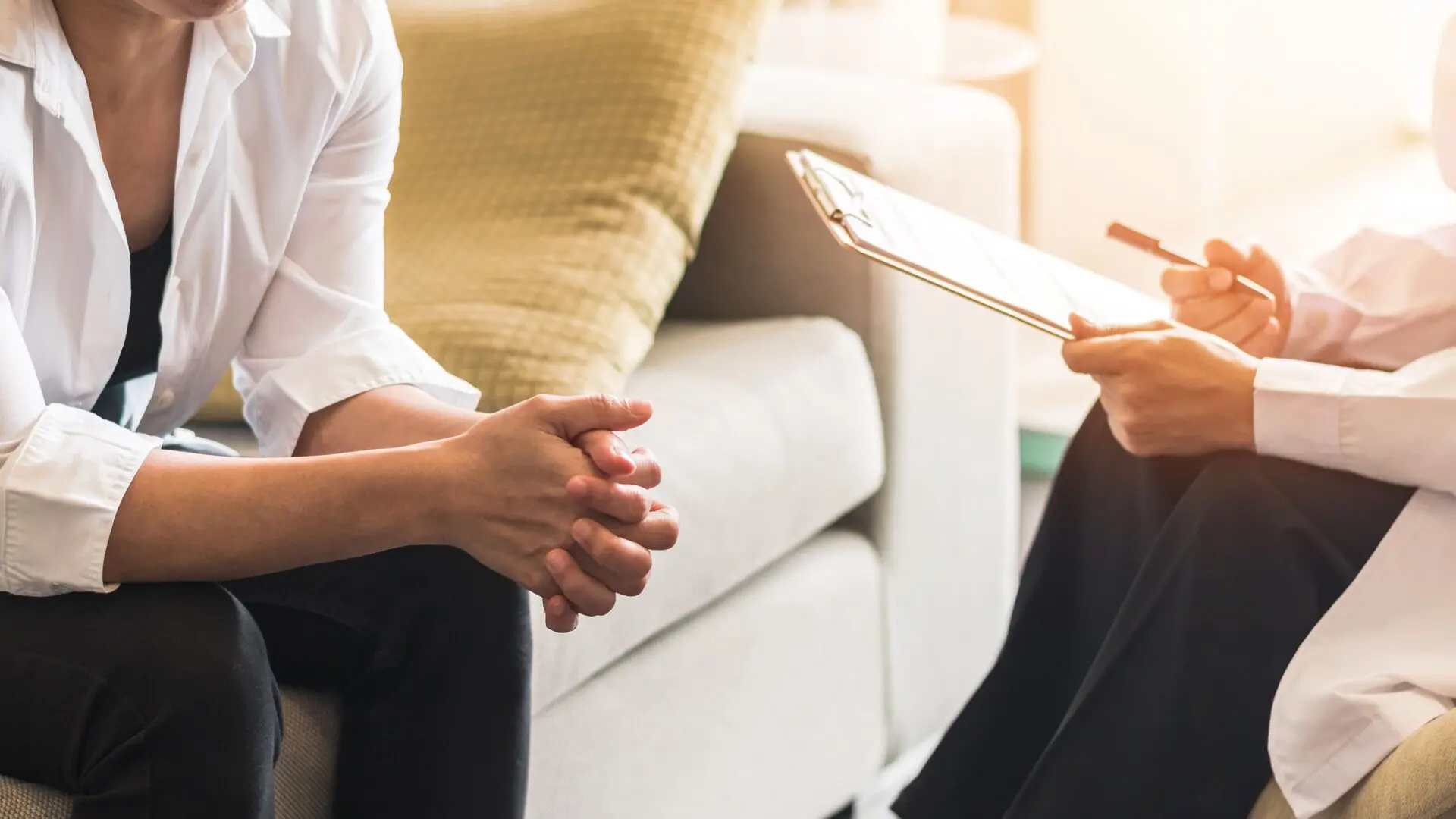 Two people sitting on a couch talking to each other.