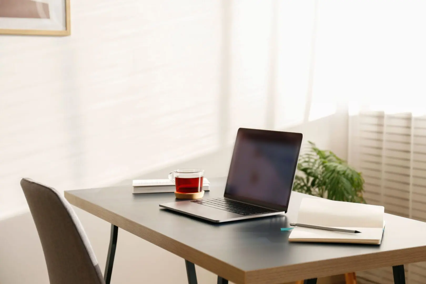 A laptop and coffee cup on a table.