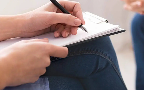 A person writing on paper with a pen.